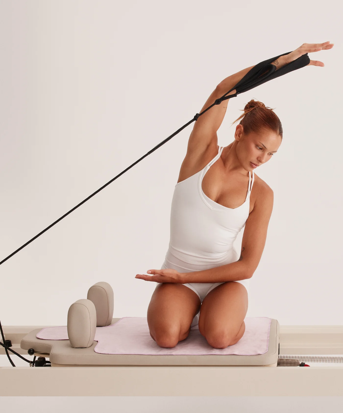 Praticante di Pilates in allungo sul Reformer — promo Bring Your Bestie